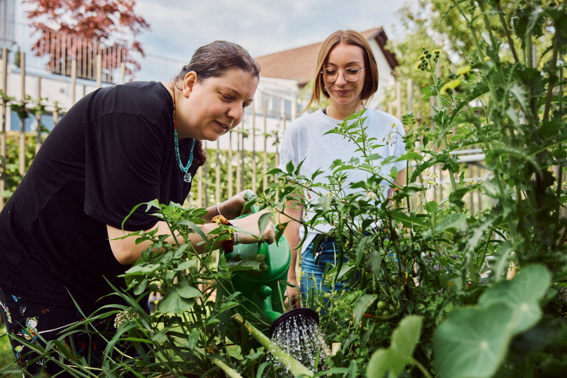 Das ist eine Bildbeschreibung: Eine Frau giesst Blumen im Garten.