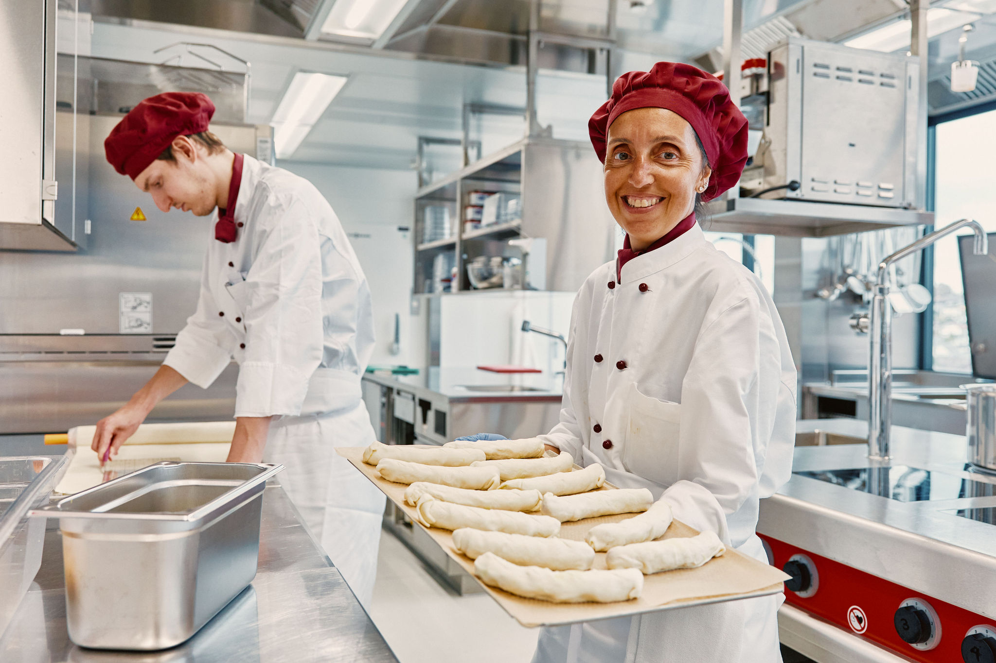 Geschuetzter Arbeitsplatz in der Kueche im Personalrestaurant Bertschi AG: Mitarbeiterin hat ein Backblech mit Gebäck auf der Hand